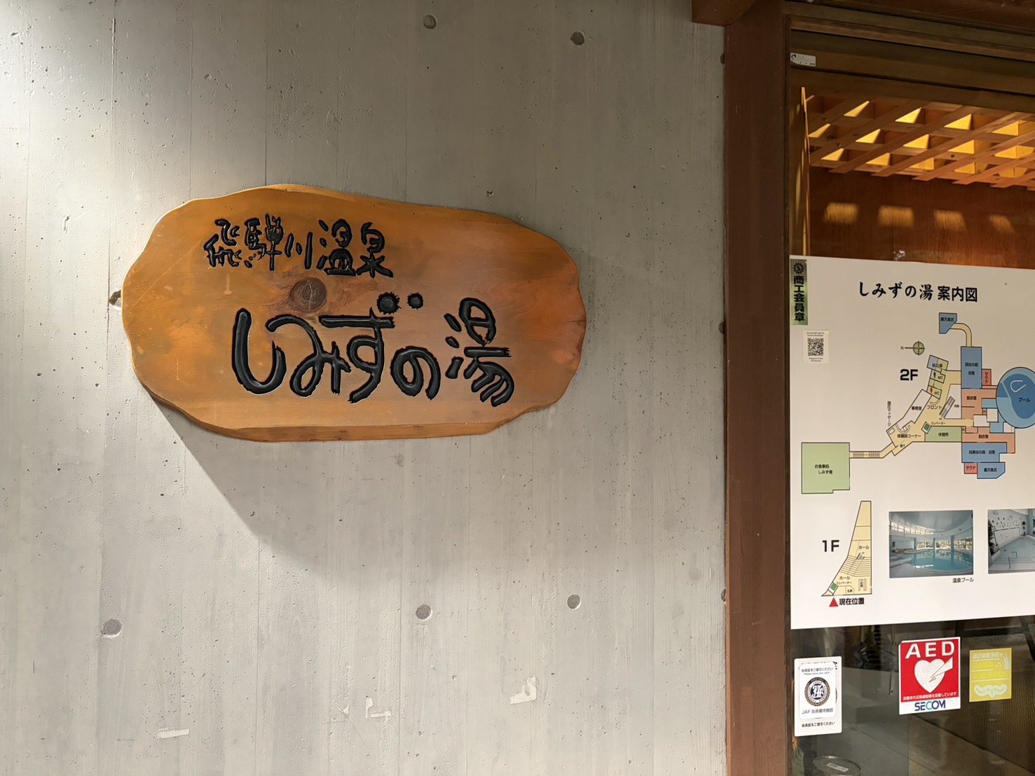 飛騨川温泉しみずの湯の入口。一枚板に彫られた「飛騨川温泉 しみずの湯」の看板