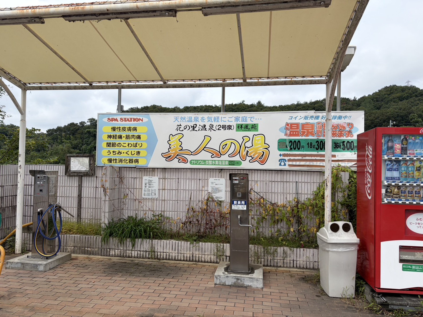 祥風苑の外にある温泉スタンドと飲用の蛇口。美人の湯の看板と持ち帰りの価格