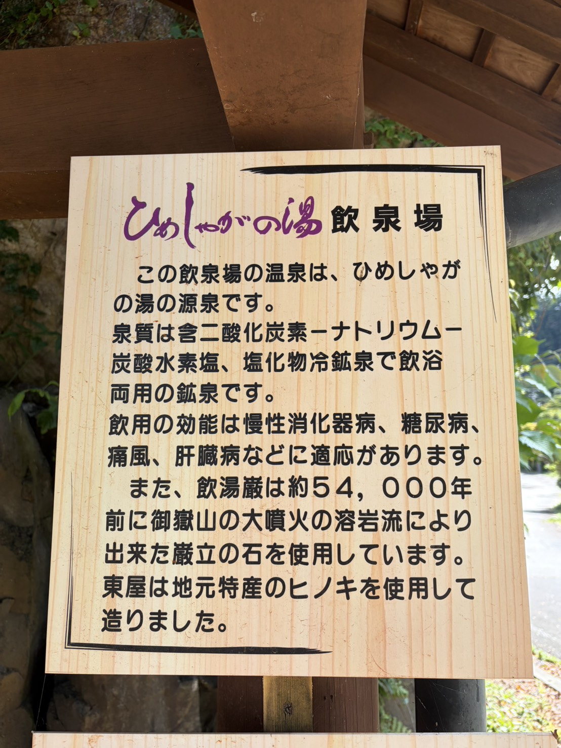 飲泉場の説明板。54000年前の御嶽山の溶岩でできた巌立の石を使っていると書かれている