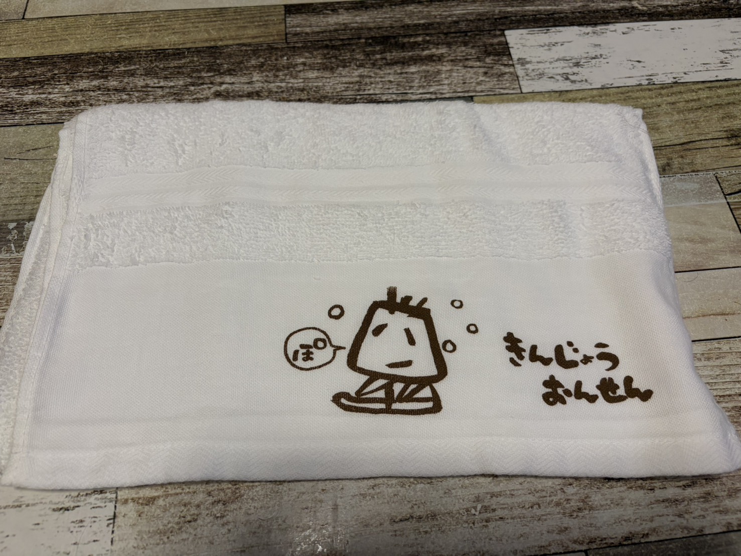 金城温泉元湯のオリジナルタオル。ぽっと湯気を出すキャラクターと「きんじょうおんせん」の文字