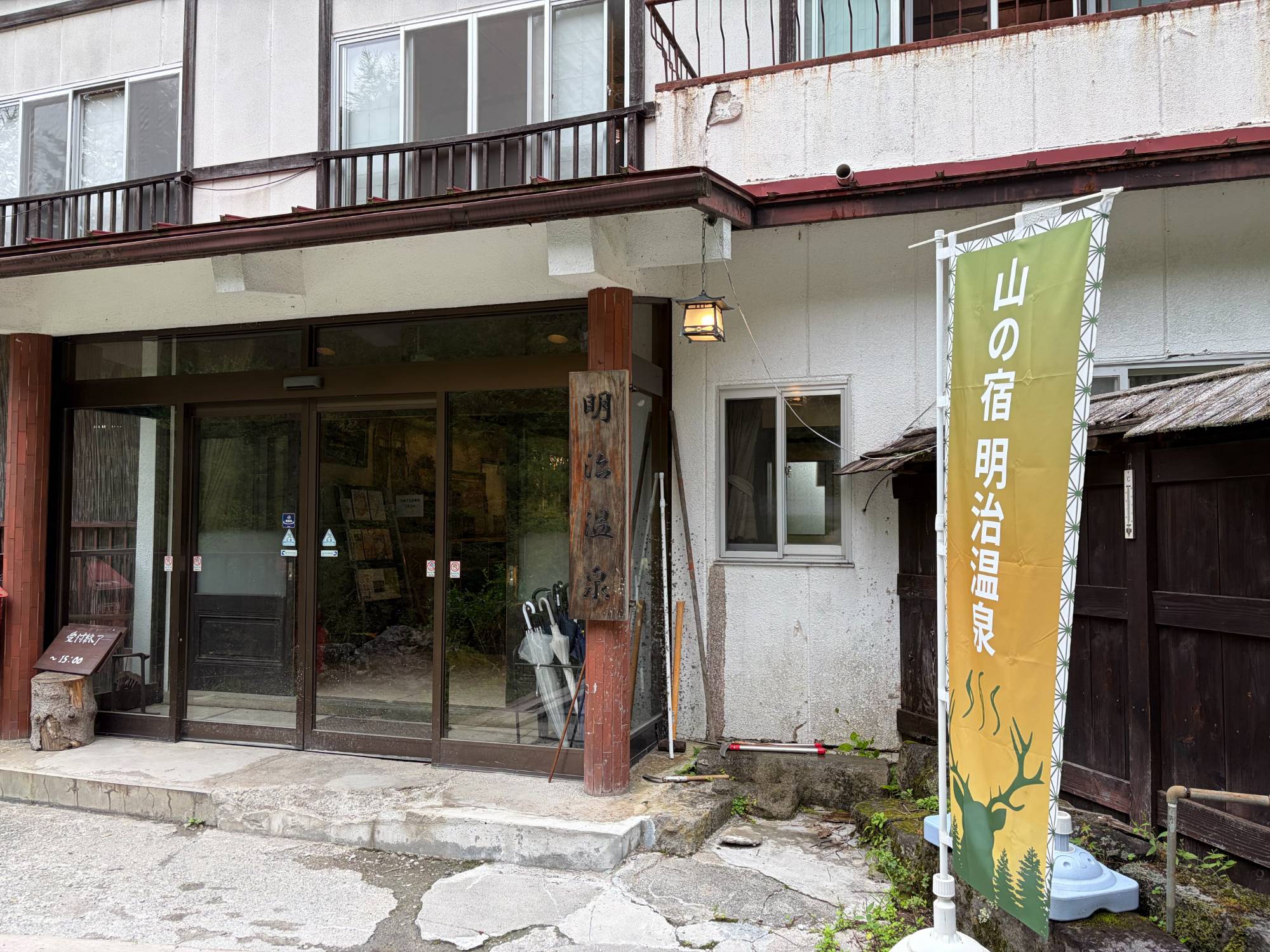 山の宿 明治温泉の玄関。木の看板と「山の宿 明治温泉」ののぼり
