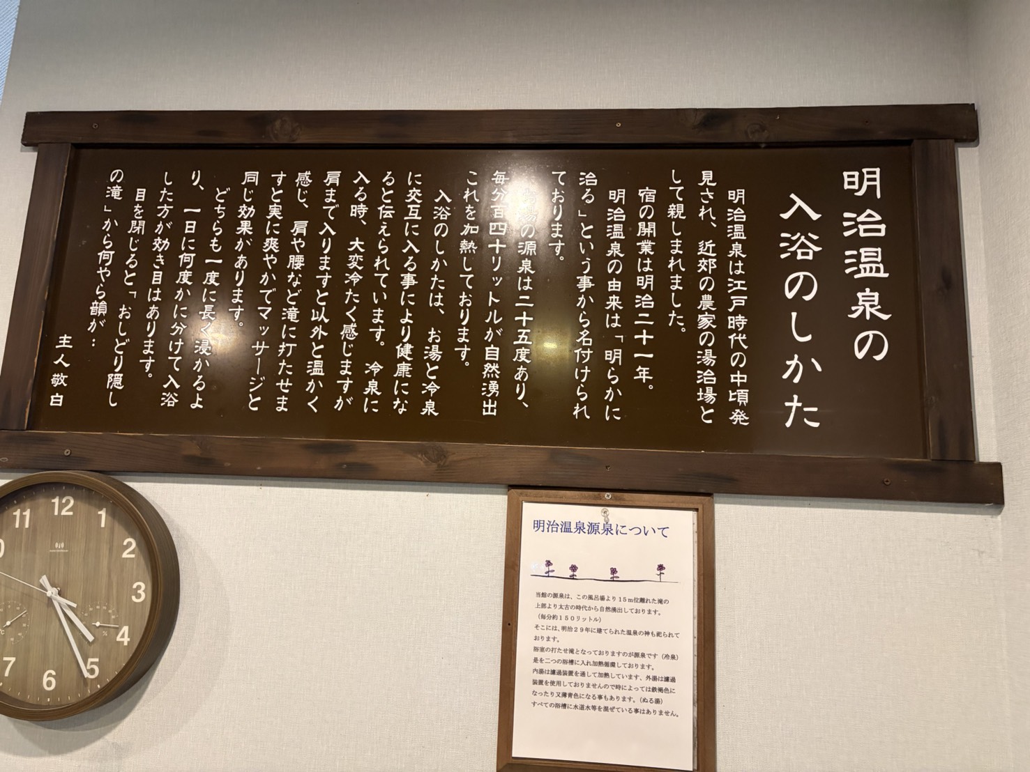 廊下に掛かった板「明治温泉の入浴のしかた」と、源泉についての説明